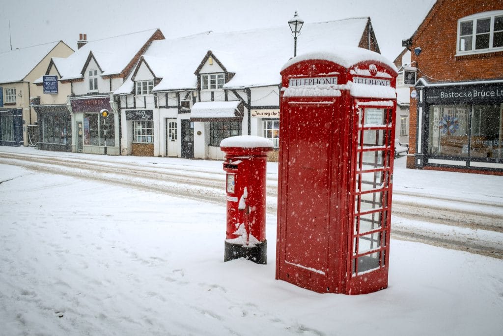 Red post and telephone box in the snow