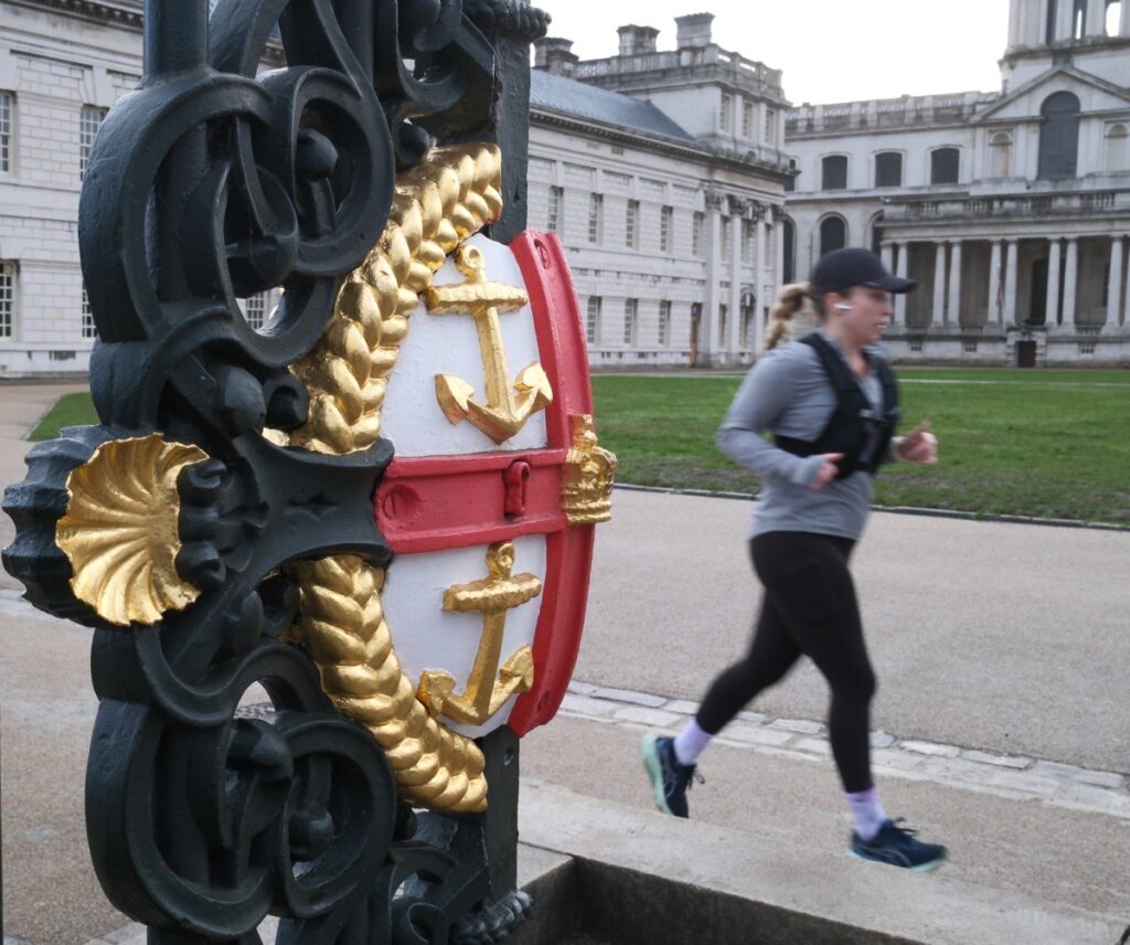 A runner passes part of the historic coat of arms at old Navy College, Greenwich.