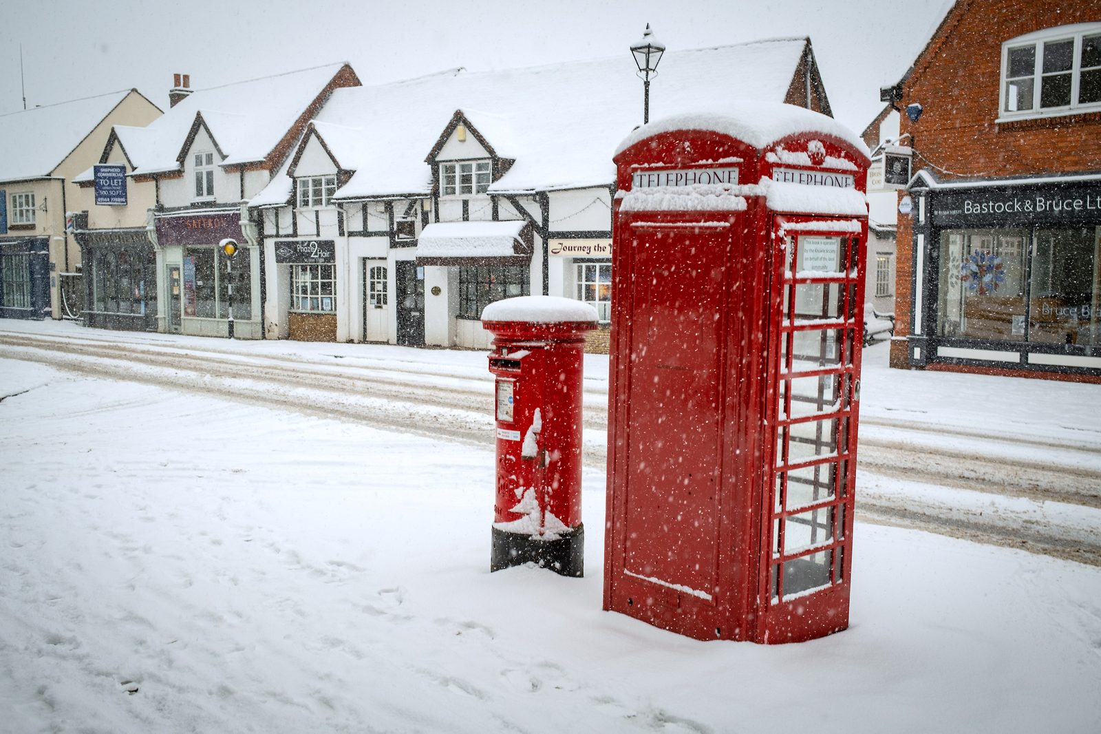 Red post and telephone box in the snow