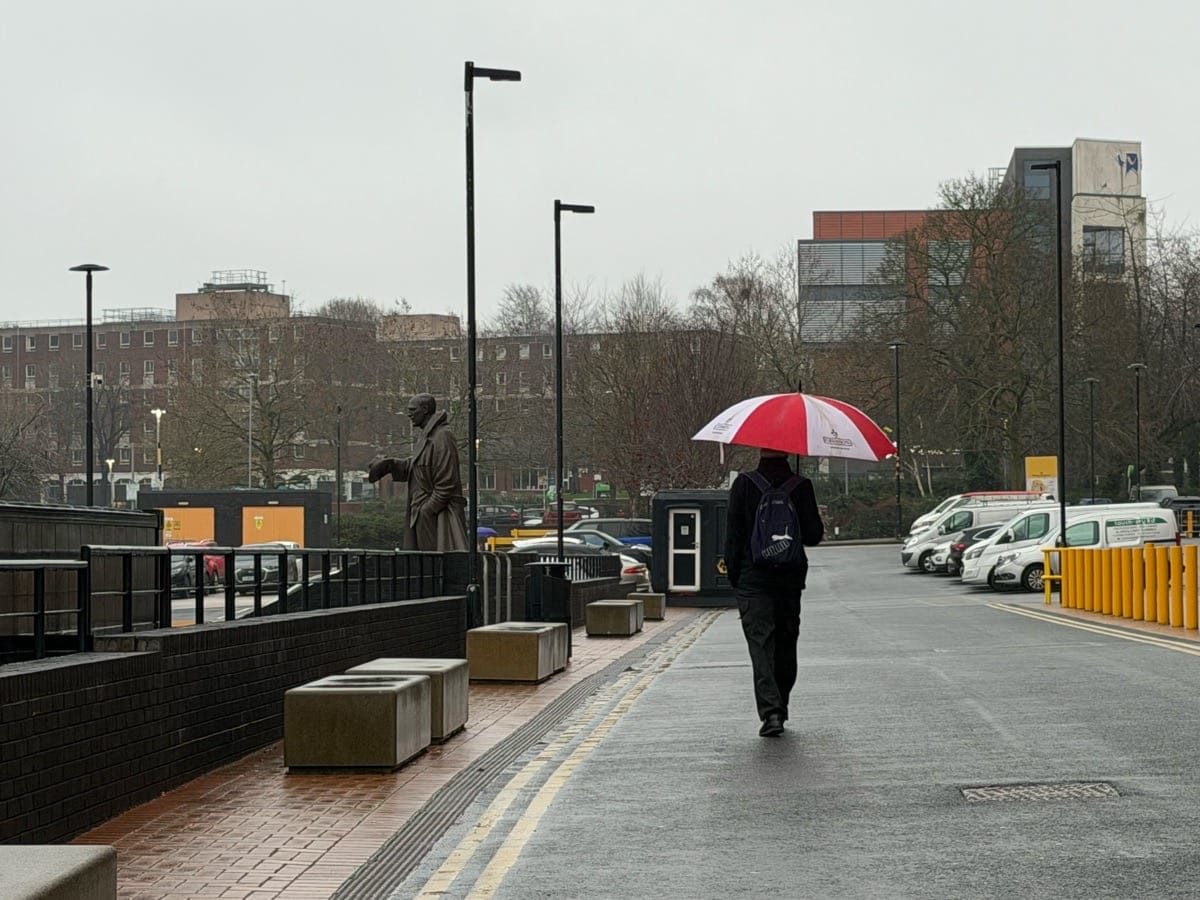 Photographing Wolverhampton, a man with an umbrella, raining outside Molineux football stadium.